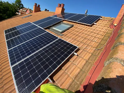 Paneles solares sobre tejado de teja junto a una claraboya en Garrapinillos