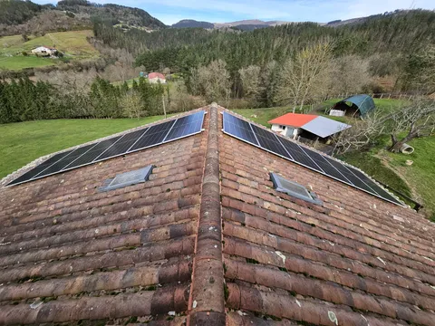 Paneles solares sobre tejado de teja con vistas al valle en Garai
