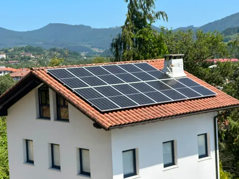 Paneles solares sobre tejado de teja con vistas al valle en Gernika-Lumo