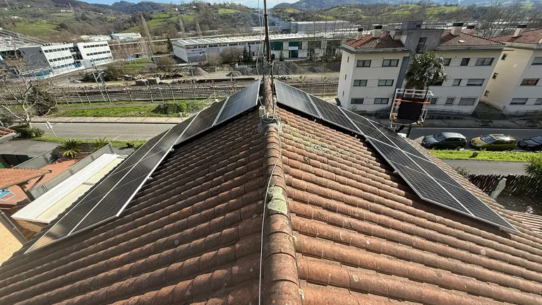 Paneles solares en las dos vertientes de un tejado con vistas a la montaña, en Hernani