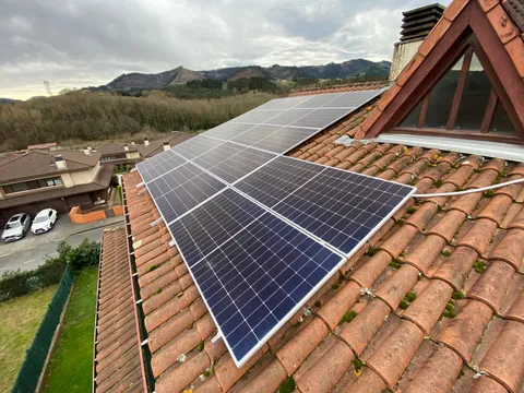 Paneles solares sobre tejado de teja con vistas al valle en Muxika