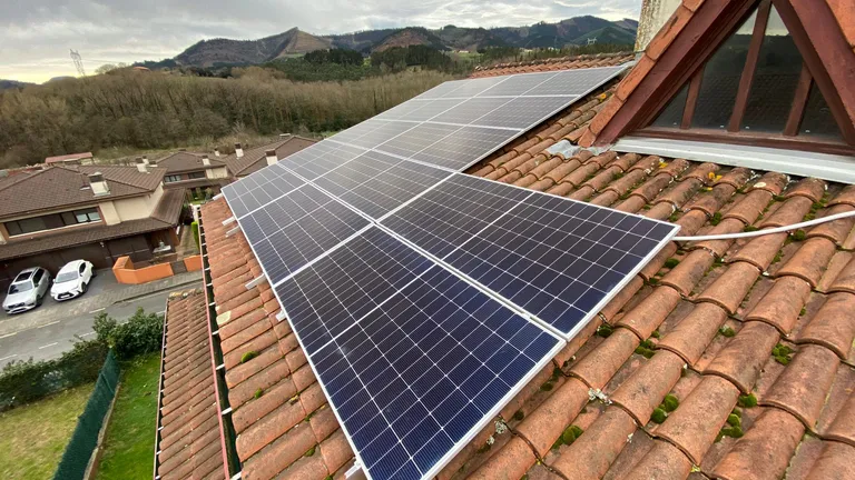 Placas solares sobre un tejado de teja con vistas al valle en Muxika, País Vasco