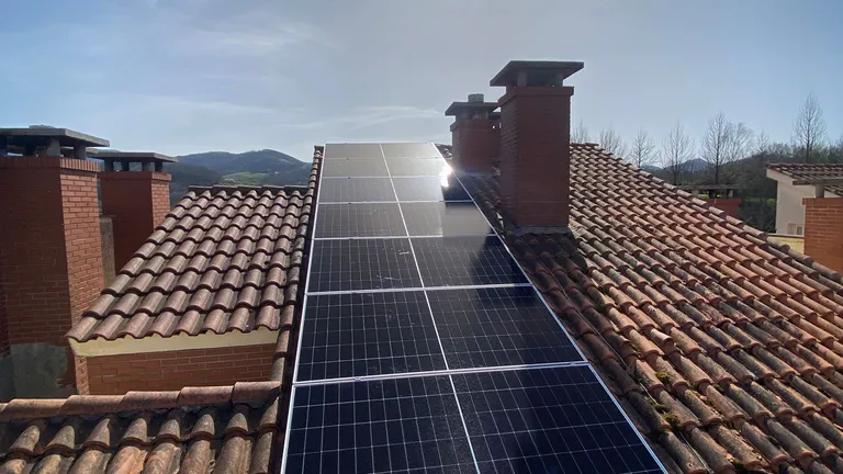 Paneles solares sobre tejado de teja entre chimeneas en Oiartzun, País Vasco