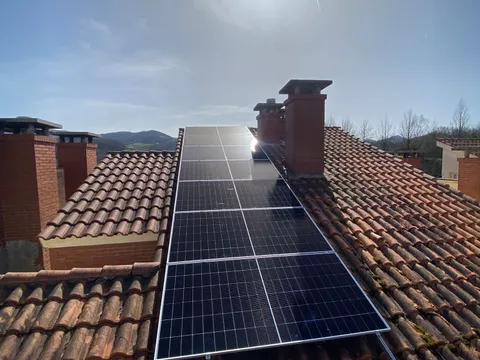 Paneles solares sobre tejado de teja entre chimeneas en Oiartzun